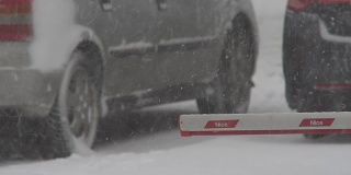 冬天。下雪时停在停车场的汽车。龙卷风期间的汽车交通。特写镜头