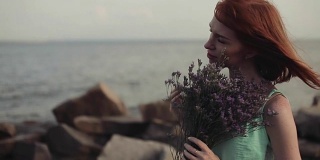 美丽性感的女孩在阳光明媚的天气里手捧鲜花在海边摆姿势