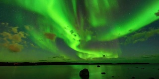 极光波段-一段延时视频的明亮波段的极光光束扫描通过星空在一个北方湖。