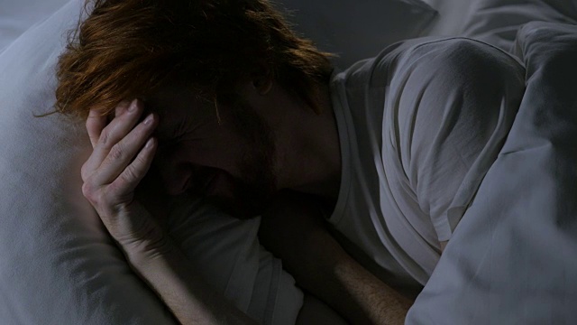 头痛，忧郁的男人睡在黑暗的房间的床上