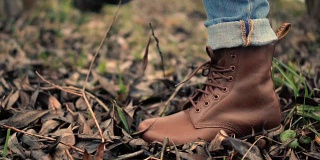 走路的腿在棕色的鞋子侧视图。穿着棕色皮靴走路的脚