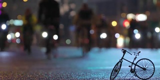 很多骑自行车的人在晚上骑自行车在模糊的自行车游行在灯光照亮城市街道的背景下，自行车timalapse的小比例模型。一群骑自行车的人。自行车交通。概念运动健康的生活方式。明亮的强光照射。低