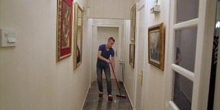 一个男人在家里用扫帚扫地
