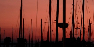 游艇剪影的背景黄昏日落在海上。游艇港口和小艇桅杆