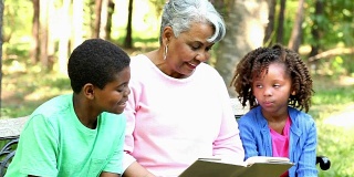 祖母和孙辈一起在户外看书或平板电脑。