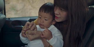 年轻的亚洲母亲带着男婴开车旅行。