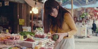 亚洲女人在市场买水果和蔬菜