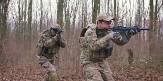 一群年轻的武装士兵在一个地区的武装冲突中穿着制服以突击步枪瞄准森林，慢镜头，软式