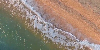 鸟瞰图:清晨海浪冲进荒芜的海滩，俯视图