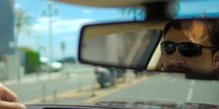 在行驶中的汽车、交通中，太阳镜在后视镜中的男性脸的反射
