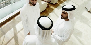 阿拉伯商人穿着传统服装见面握手