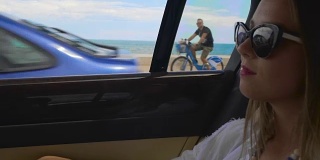成功的女人坐在汽车后座沿着海滨度假城市