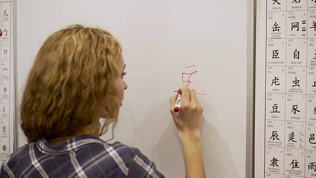 一名年轻女子用记号笔在白板上写象形文字