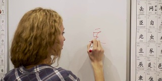 一名年轻女子用记号笔在白板上写象形文字