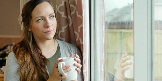 年轻漂亮的白人女人一边喝着咖啡一边凝视着窗外