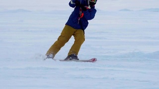 慢动作:一名男运动员正在滑雪板上放风筝。他在一个大湖的冰面上打滚。翻滚时，他会进行各种跳跃、动作和其他练习。雪板上的雪向不同的方向飞舞。视频素材模板下载