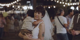快乐的女人在婚礼上抱着她的儿子玩。
