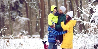 爱的家庭-妈妈，爸爸，女儿和儿子拥抱在白雪覆盖的树的背景