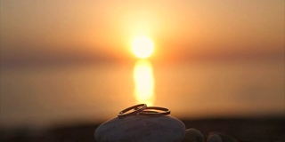 结婚戒指在日落的沙滩上，浪漫和爱情的概念