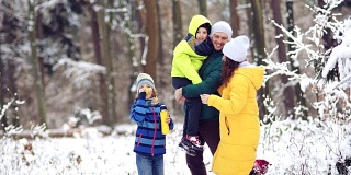 冬日森林里的全家福。幸福的家庭和宠物在白雪覆盖的树的背景下