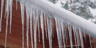 在冬季森林的某个地方，长长的冰柱悬挂在木屋的屋顶上