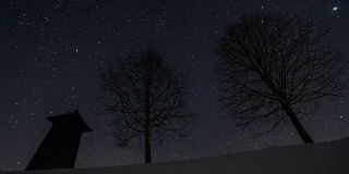 星星在夜空中移动，木制的钟楼和树木的剪影在冬天，天文时间流逝，摄影