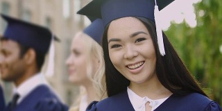 在毕业典礼上，亚洲女孩在照相机前微笑
