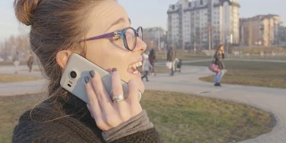 一个女孩在智能手机上走路和说话的特写慢动作镜头
