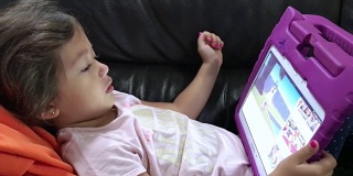 可爱的小女孩躺在平板电脑