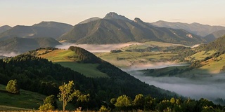 日出时，阳光掠过多雾的山谷。薄雾清晨在美丽的乡村景观时间流逝