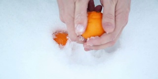一个男人正在把橘子从雪地上擦去。