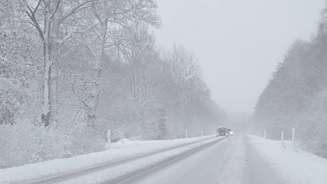冬季驾驶-在一个多雾的日子里，大雪下的乡村道路上迎面而来的车辆