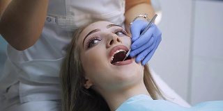 女牙医使用牙科工具-显微镜，镜子和探针在牙科诊所治疗病人的牙齿。医学、牙科和保健概念。牙科设备