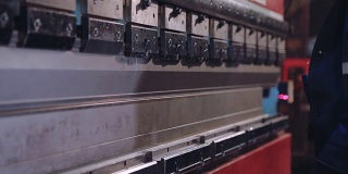 工人在工厂的现代弯曲工业机器上弯曲金属板。数控