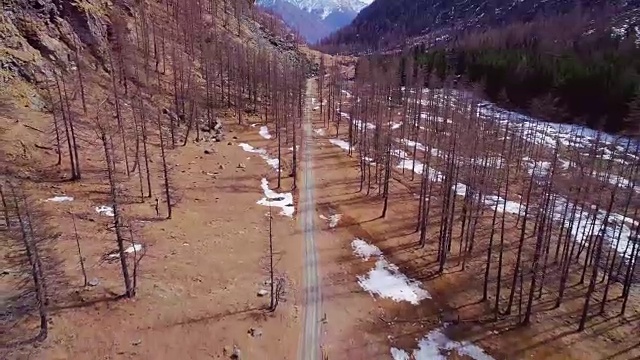 空中飞行，向后飞行，飞越黄山山谷小屋附近的小路和森林森林。秋冬户外雪野自然景观。4k无人机飞行建立