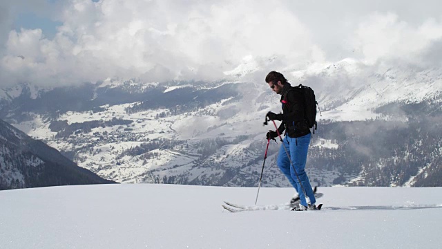 人沿雪岭上行上行景观。登山滑雪活动。冬季滑雪者在高山户外运动。侧视图。慢动作60p 4k视频