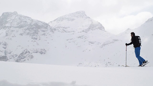 男人和女人沿着雪岭风景走上去。登山滑雪活动。冬季滑雪者在高山户外运动。侧视图。慢动作60p 4k视频