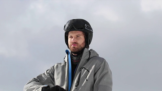 戴着头盔的人关闭软壳夹克准备滑雪。登山滑雪活动。冬季滑雪者在高山户外运动。前视图。慢动作60p 4k视频
