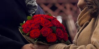 一名男子向女友献上一束鲜花，温柔地拥抱相爱的情侣