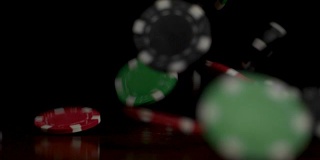 掉落的扑克筹码孤立在黑色背景上。彩色扑克筹码落在桌子上的黑色背景。玩着筹码在黑色背景中飞舞