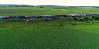 一列长长的货运火车在绿色的田野中行驶。