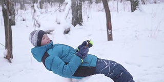 小孩慢动作跌入雪中。活跃在户外运动。冬天的阳光灿烂的日子