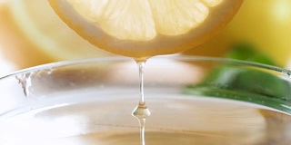 特写慢镜头的果汁滴慢慢地从柠檬片在茶杯