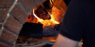 一个男人把披萨放到砖炉里的慢镜头