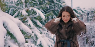 深褐色的女孩穿着棕色的毛皮大衣在冬天慢动作的走着