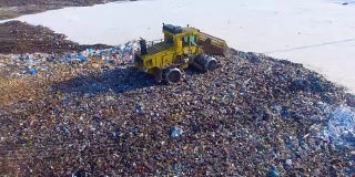 垃圾填埋场推土机在垃圾堆边缘移动。