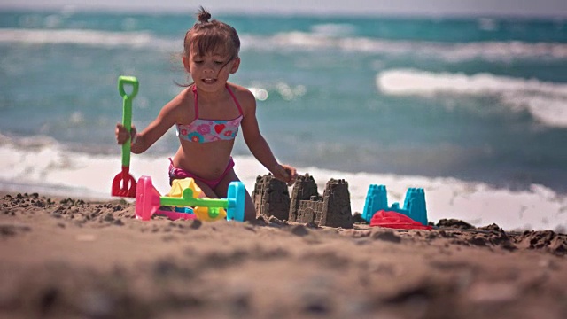 快乐的中国女孩在沙滩上玩，建沙堡