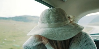 一个戴着帽子的女人坐在汽车后座上，看到了一些可怕的东西