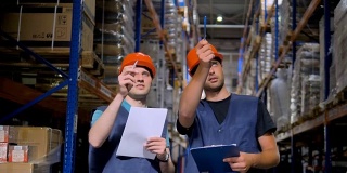 两个仓库员工一边聊天一边做笔记。