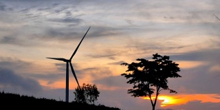 4K美丽的风力涡轮机在黄昏日落。农村玉米田可再生能源生产的概念
